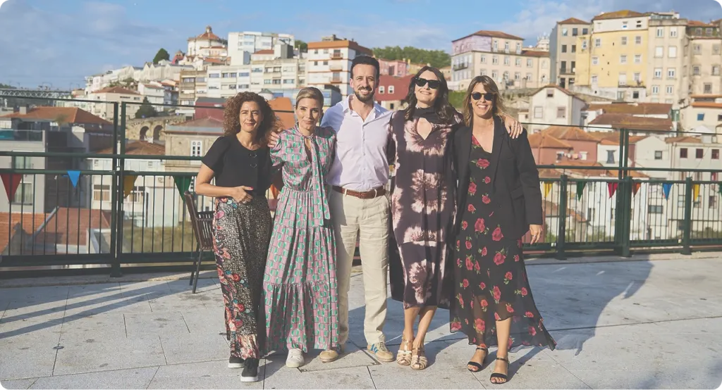 Group of people smiling on rooftop with city view.