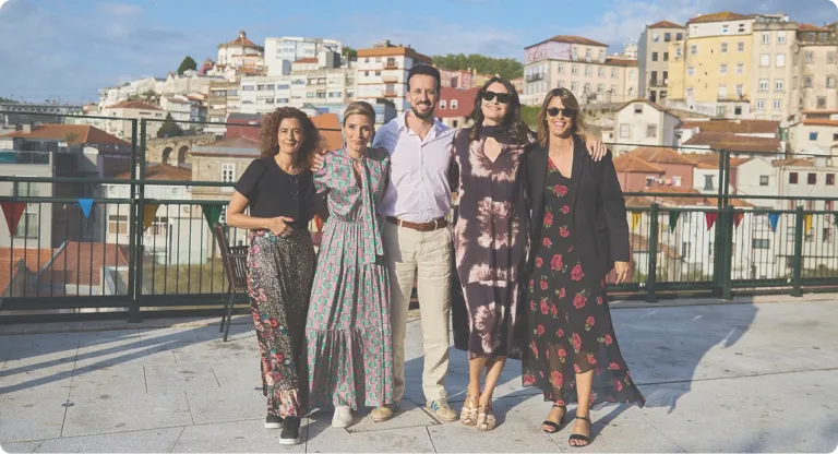 Group of people smiling on rooftop with city view.